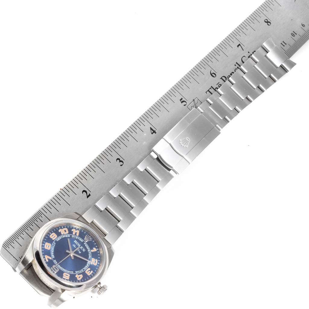 The image shows a top-down view of a Rolex Air-King 114200 Men's Stainless Steel Blue Dial 114200 Men's Stainless Steel Blue Dial watch including its face, metallic strap, and clasp alongside a ruler for scale.