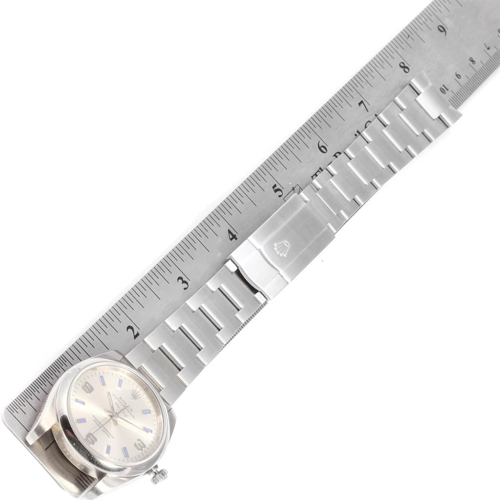 The image shows the Rolex Air-King 114200 Men's Stainless Steel Silver Dial 114200 Men's Stainless Steel Silver Dial watch laid flat next to a ruler, displaying its face, bracelet, and clasp.