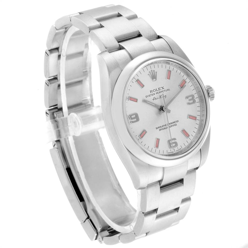 The Rolex 114200 Stainless Steel Silver Dial 114200 Stainless Steel Silver Dial Air King 114200 model is shown at a three-quarter angle, displaying its silver dial, pink baton markers, and metal bracelet.