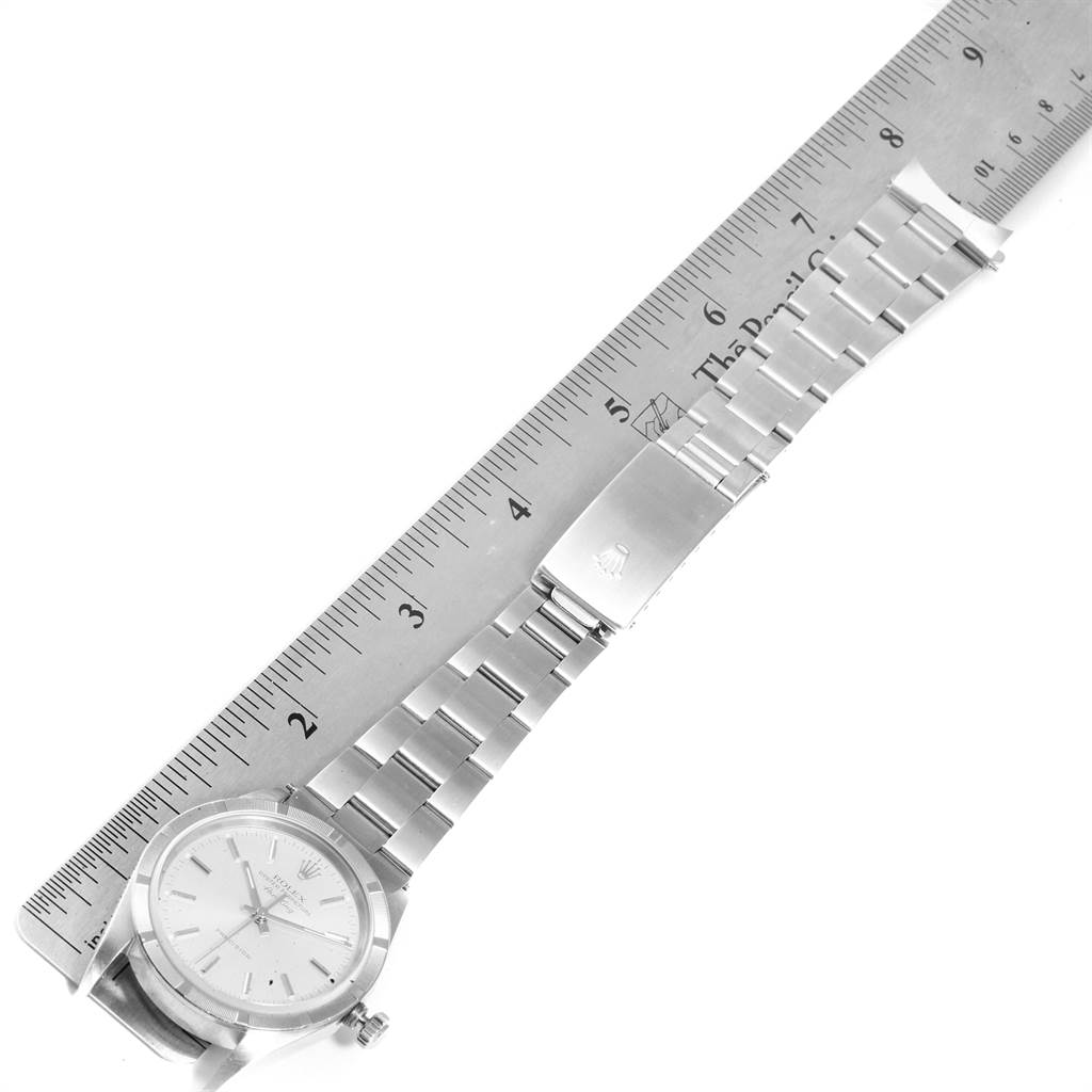 The Rolex Air-King 14010 Men's Stainless Steel Silver Dial 14010 Men's Stainless Steel Silver Dial watch is displayed flat with a full view of its face, bracelet, and clasp, alongside a ruler for scale.