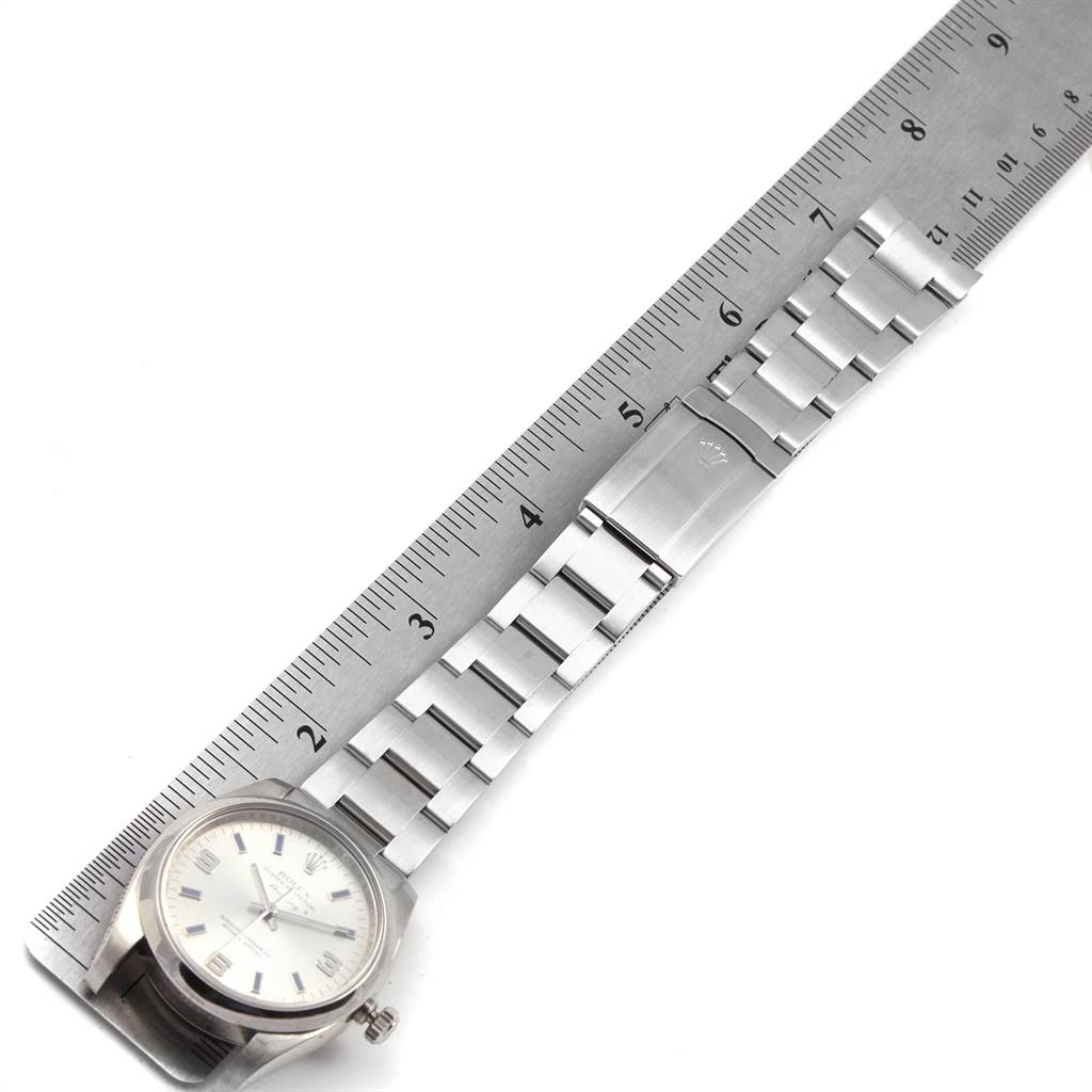 The Rolex Air-King 114200 Men's Stainless Steel Silver Dial 114200 Men's Stainless Steel Silver Dial watch is shown from above, displaying the dial, case, bracelet, and clasp alongside a ruler for scale.