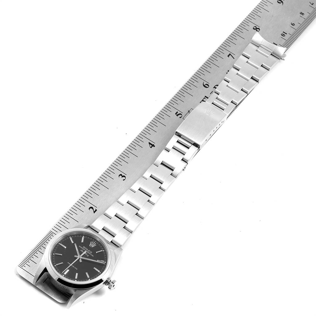 The image shows a top-down view of a Rolex Air-King 14000 Men's Stainless Steel Black Dial 14000 Men's Stainless Steel Black Dial model watch with a metal strap, lying next to a ruler for measurement.