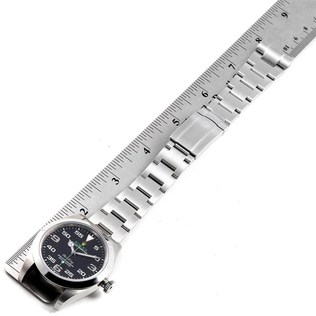 The Rolex Air-King 116900 Men's Stainless Steel Black Dial 116900 Men's Stainless Steel Black Dial watch is shown from a top-down angle, displaying the face, bezel, case, and bracelet alongside a measuring ruler.