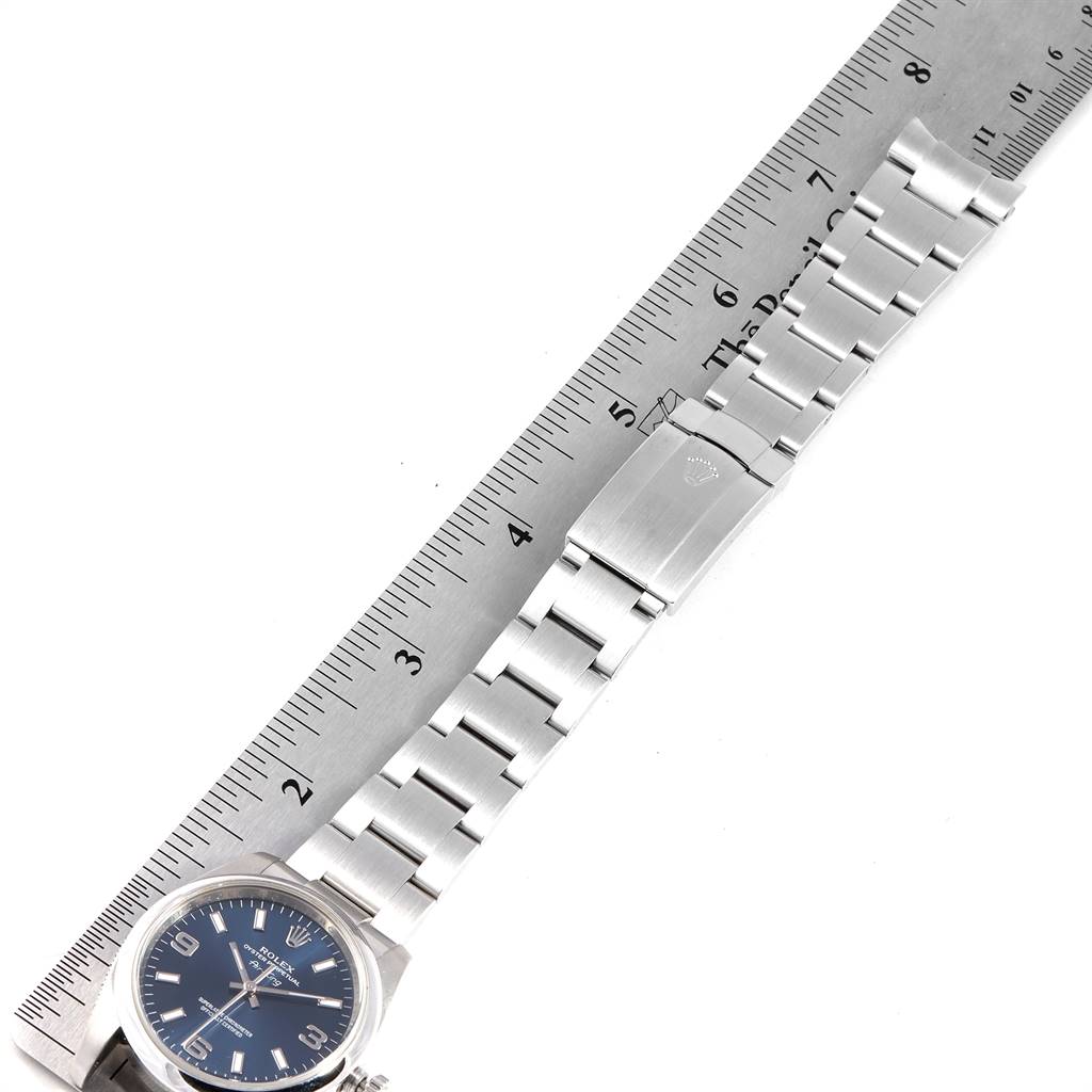 This image shows the entire length of a Rolex Air-King 114200 Men's Stainless Steel Blue Dial 114200 Men's Stainless Steel Blue Dial watch measured against a ruler, displaying its bracelet and clasp.
