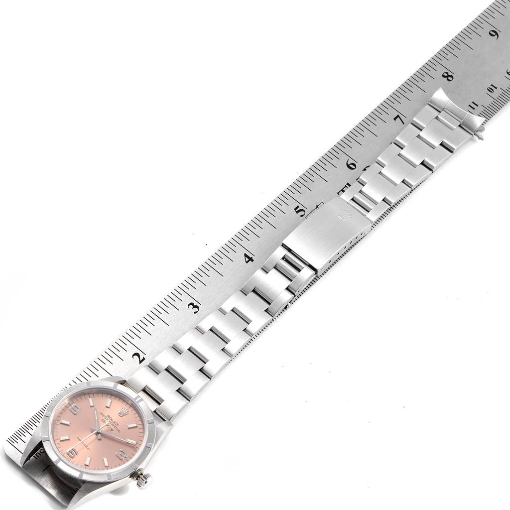 The Rolex Air-King 14010 Men's Stainless Steel Pink Dial 14010 Men's Stainless Steel Pink Dial watch is shown from a top-down angle, including its face, strap, and part of a ruler displaying measurements.