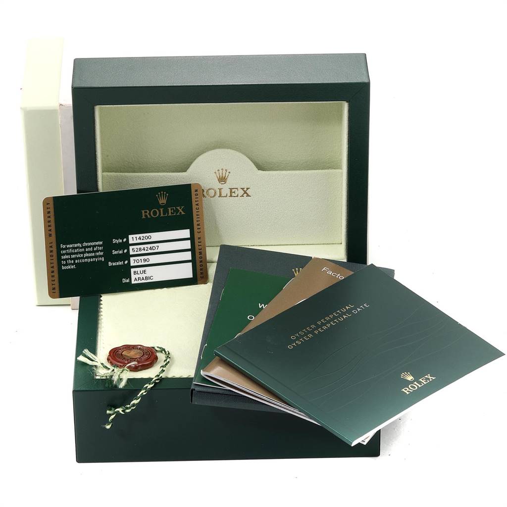 The image shows the packaging and accessories for a Rolex Air-King 114200 Men's Stainless Steel Blue Dial 114200 Men's Stainless Steel Blue Dial, including the box, booklets, a card, and a seal.