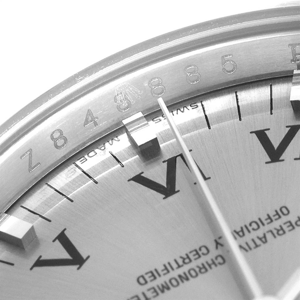 This close-up image of the Rolex Air-King 114210 Men's Stainless Steel Grey Dial 114210 Men's Stainless Steel Grey Dial watch displays part of its dial, Roman numeral markers, and a portion of the case.