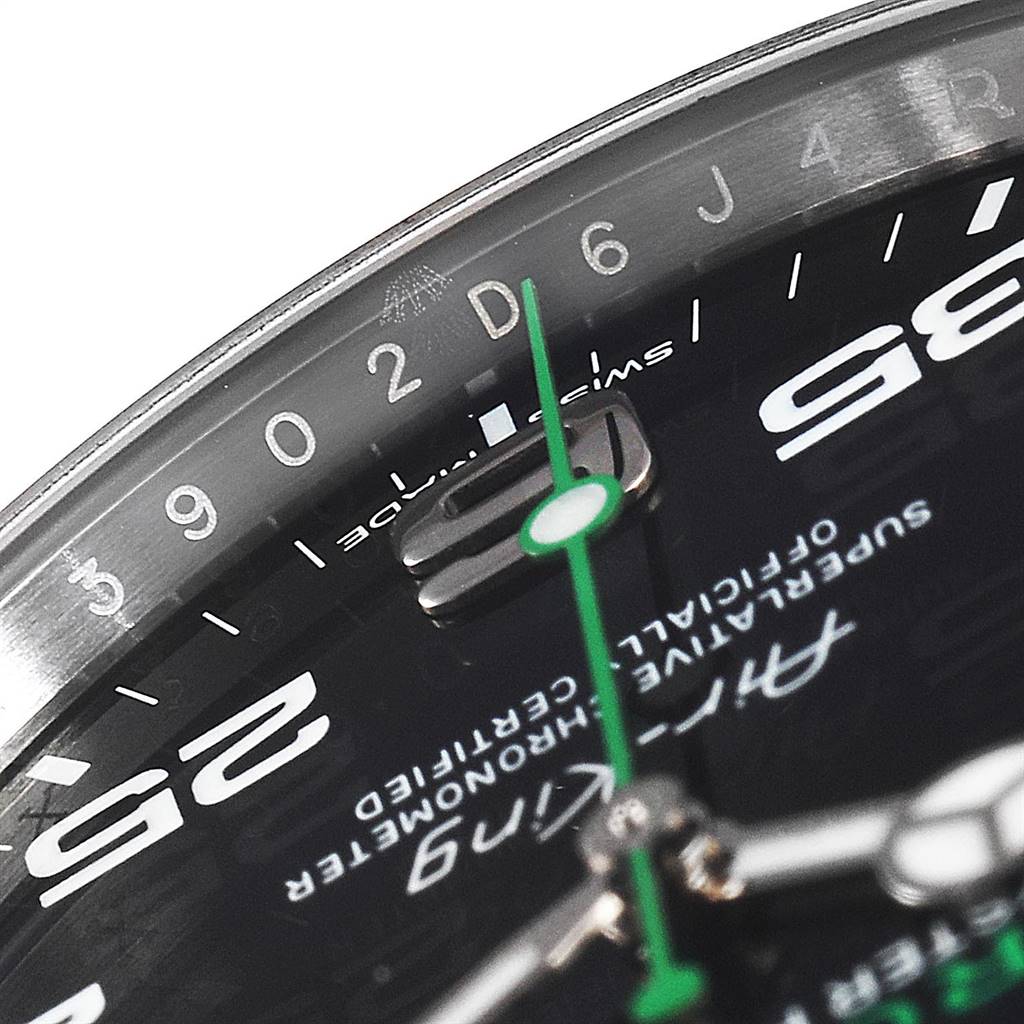 This close-up image of a Rolex Air-King 116900 Men's Stainless Steel Black Dial 116900 Men's Stainless Steel Black Dial watch shows the dial, green second hand, and markings on the chapter ring.