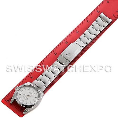 The Rolex Air-King 114200 Men's Stainless Steel Silver Dial 114200 Men's Stainless Steel Silver Dial watch is shown from a top-down angle, showcasing the full face, bracelet, and clasp next to a red ruler.