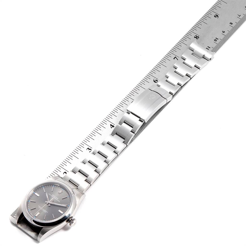 The Rolex Oyster Perpetual 114300 Men's Stainless Steel Silver Dial 114300 Men's Stainless Steel Silver Dial watch is shown from the front, featuring its dial and metal bracelet beside a ruler for measurement.