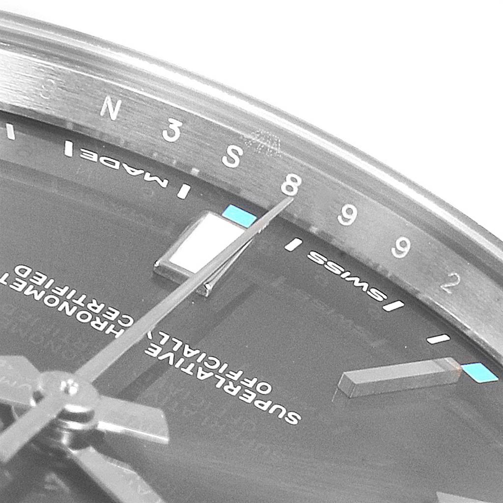 This close-up of the Rolex Oyster Perpetual 114300 Men's Stainless Steel Silver Dial 114300 Men's Stainless Steel Silver Dial watch shows the dial, hour markers, and part of the minute hand.