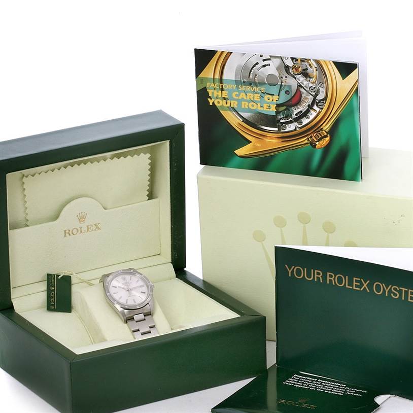 The Rolex Air-King 14010 Men's Stainless Steel Silver Dial 14010 Men's Stainless Steel Silver Dial watch is displayed in its box at an angle showing the face and bracelet, with booklets and packaging in the background.