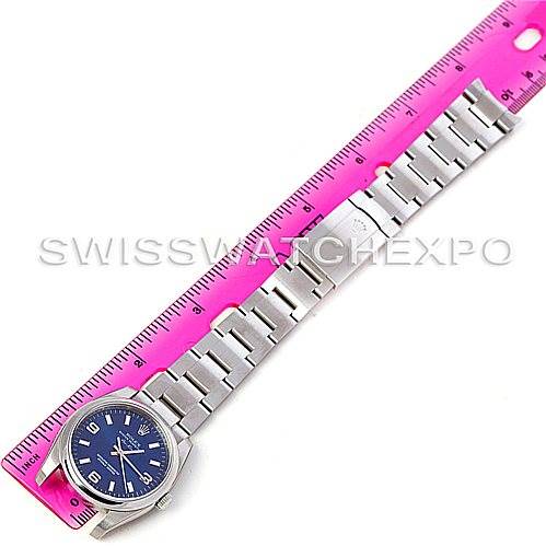The Rolex Air-King 114200 Men's Stainless Steel Blue Dial 114200 Men's Stainless Steel Blue Dial watch is shown flat with its bracelet extended alongside a pink ruler for scale.