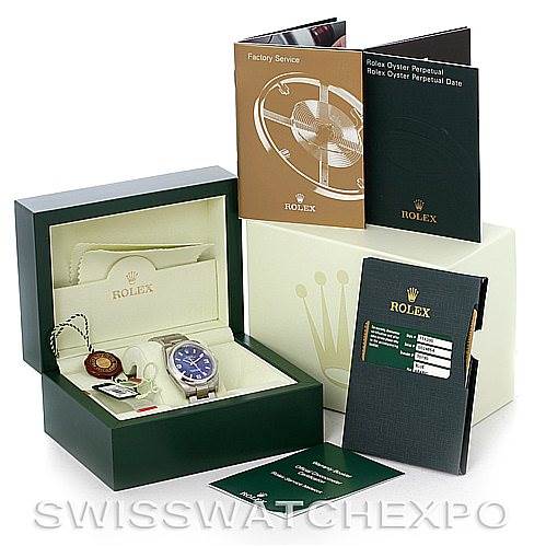 The Rolex Air-King 114200 Men's Stainless Steel Blue Dial 114200 Men's Stainless Steel Blue Dial watch is shown in its box with booklets, warranty card, and tags displayed around it.