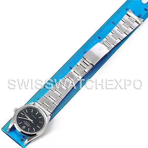 The Rolex Air-King 14000 Men's Stainless Steel Black Dial 14000 Men's Stainless Steel Black Dial watch is shown from a top-down angle, displaying the black dial, silver bracelet, and clasp placed on a blue ruler.