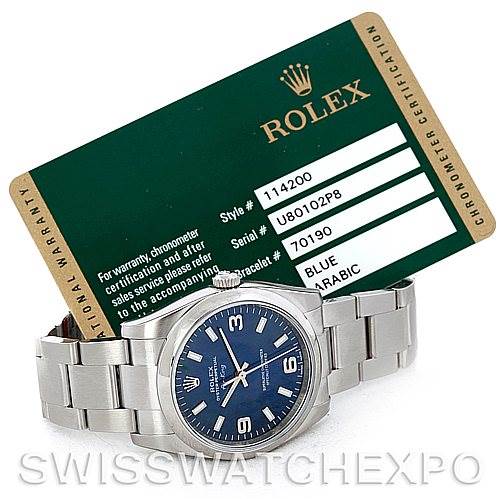 This image shows a Rolex Air-King 114200 Men's Stainless Steel Blue Dial 114200 Men's Stainless Steel Blue Dial watch laid flat, highlighting its band and face, along with its certification card in the background.