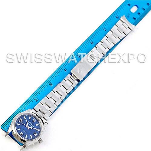 The image shows an overhead view of a Rolex Air-King 14000 Men's Stainless Steel Blue Dial 14000 Men's Stainless Steel Blue Dial watch with a blue dial and a metal bracelet, alongside a blue ruler for measurement.