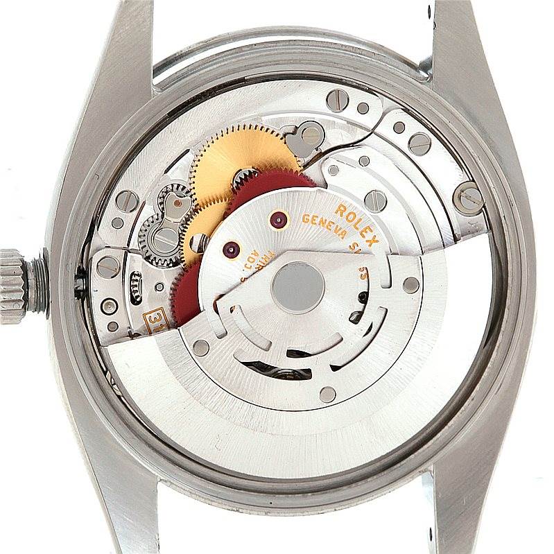The image shows the internal mechanism of a Rolex Air-King 114200 Men's Stainless Steel Silver Dial 114200 Men's Stainless Steel Silver Dial watch viewed from the back, revealing gears and the movement components.