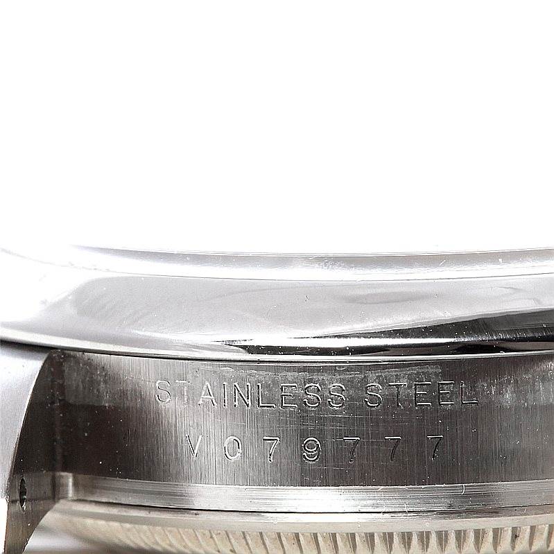 The image shows a close-up of the side of a Rolex Air-King 114200 Men's Stainless Steel White Dial 114200 Men's Stainless Steel White Dial watch case with the stainless steel marking and serial number engraved.