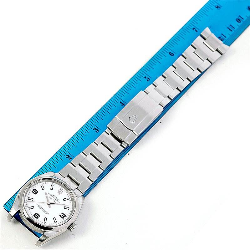 The image shows a top-down view of a Rolex Air-King 114200 Men's Stainless Steel White Dial 114200 Men's Stainless Steel White Dial watch and its metal bracelet next to a blue ruler for scale.