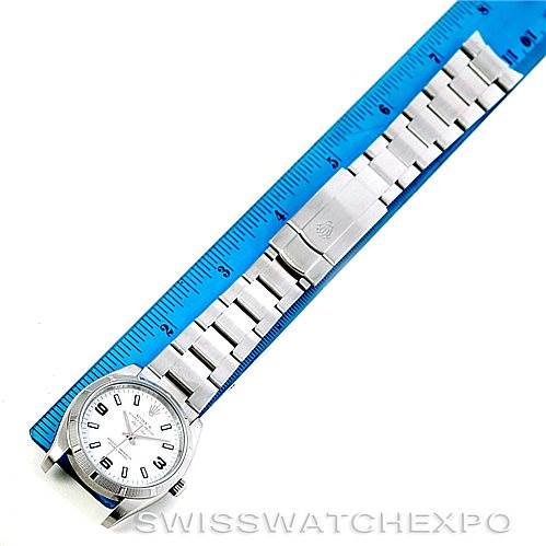 The image shows a top-down view of a Rolex Air-King 114210 Men's Stainless Steel White Dial 114210 Men's Stainless Steel White Dial watch, including its face, bracelet, and clasp, alongside a blue ruler.