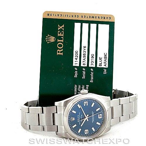 A Rolex Air-King 114200 Men's Stainless Steel Blue Dial 114200 Men's Stainless Steel Blue Dial watch is shown at a slight angle with its certification card upright behind it.
