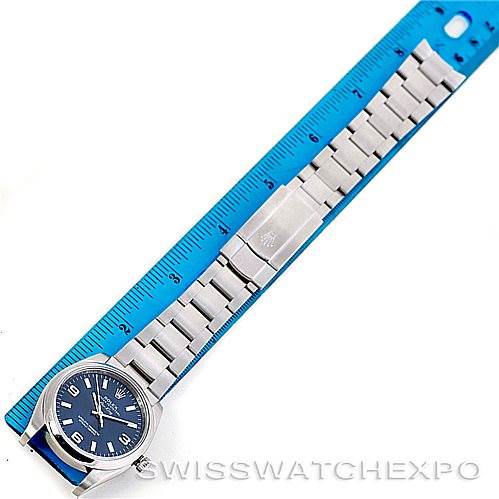 The image shows a Rolex Air-King 114200 Men's Stainless Steel Blue Dial 114200 Men's Stainless Steel Blue Dial watch laid flat next to a blue ruler, displaying the face, bracelet, and clasp from a top-down angle.