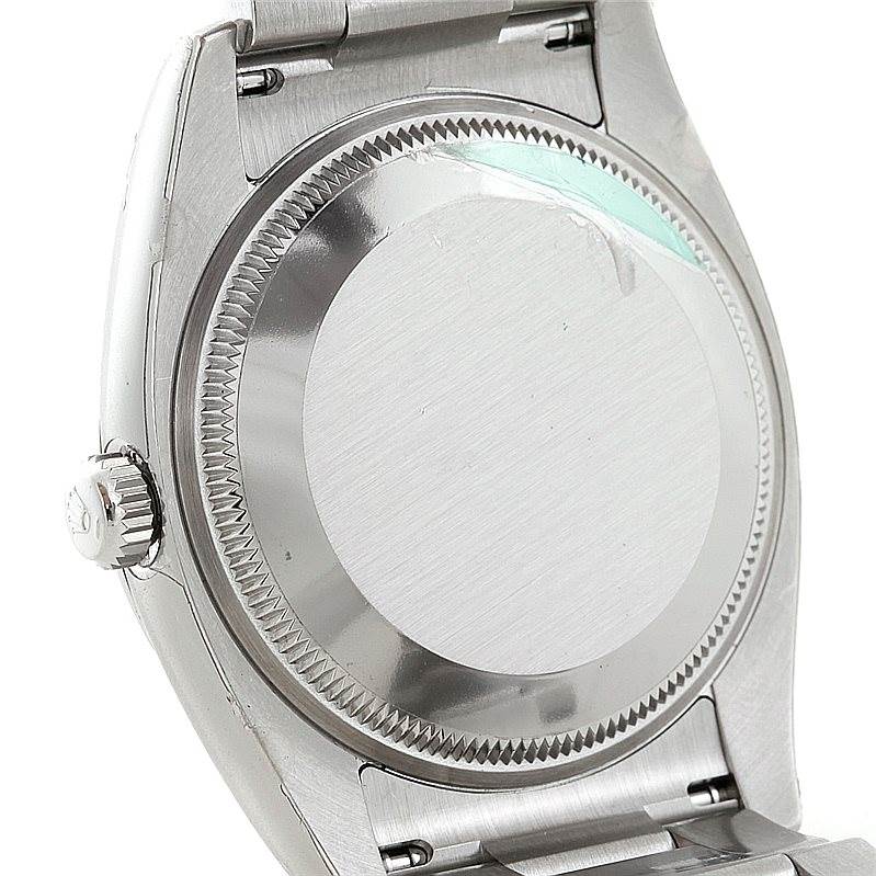 The photo shows the back case and part of the strap of a Rolex Air-King 114200 Men's Stainless Steel Blue Dial 114200 Men's Stainless Steel Blue Dial watch from a slightly angled side view.