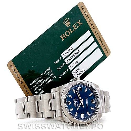 The image shows a Rolex Air-King 114200 Men's Stainless Steel Blue Dial 114200 Men's Stainless Steel Blue Dial watch face, band, and a certification card positioned at an angle behind it.