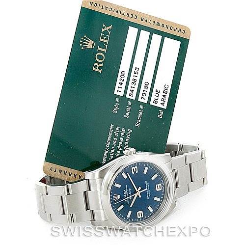 The image shows a Rolex Air-King 114200 Men's Stainless Steel Blue Dial 114200 Men's Stainless Steel Blue Dial watch placed next to its certification card, displaying the watch face, bracelet, and clasp.
