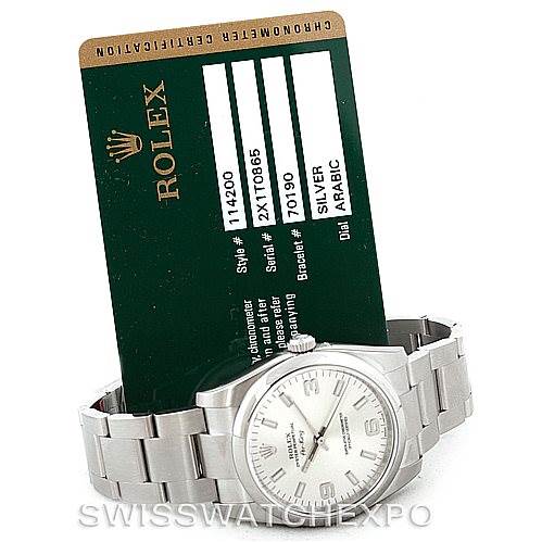 The image shows a Rolex Air-King 114200 Men's Stainless Steel Silver Dial 114200 Men's Stainless Steel Silver Dial watch laying flat with its warranty card standing behind it.