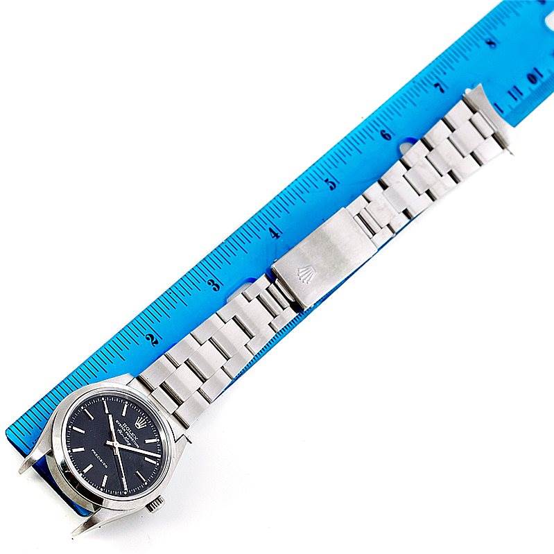 This image shows an overhead view of a Rolex Air-King 14000 Men's Stainless Steel Black Dial 14000 Men's Stainless Steel Black Dial watch, displaying the face, case, and metal bracelet beside a blue ruler.