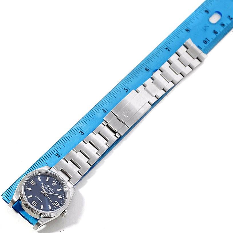 This image shows the entire Rolex Air-King 114210 Men's Stainless Steel Blue Dial 114210 Men's Stainless Steel Blue Dial watch, including the face, bezel, bracelet, and clasp, positioned next to a ruler.