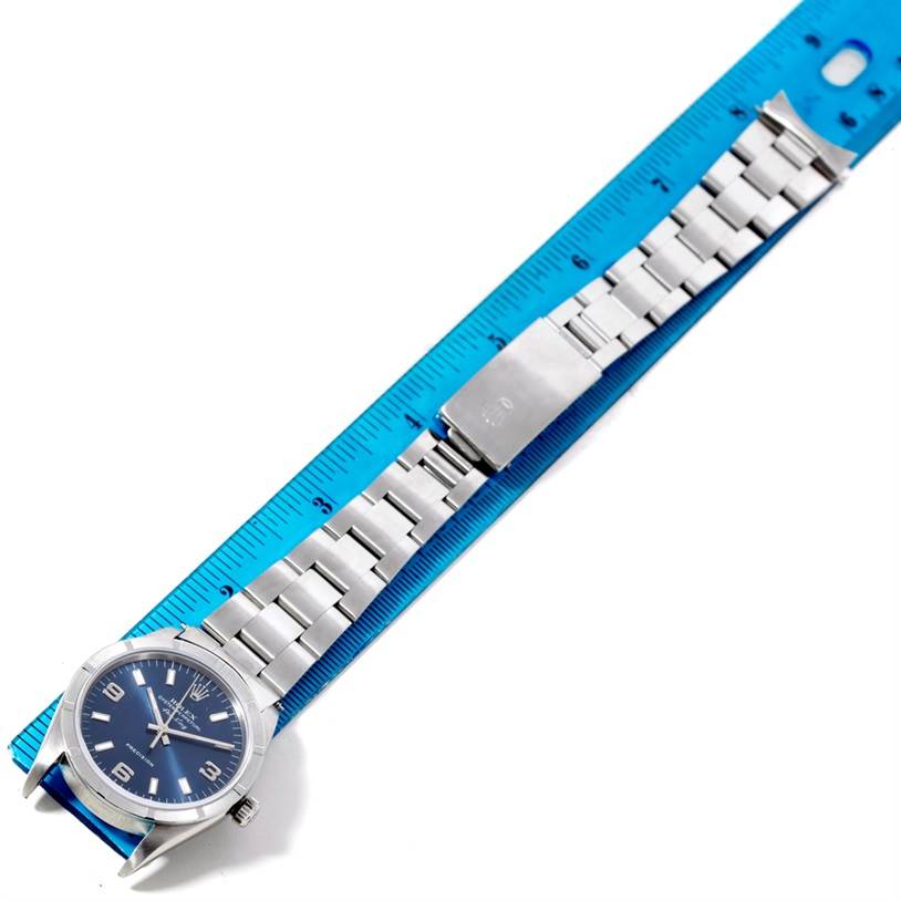 The Rolex Air-King 14010 Men's Stainless Steel Blue Dial 14010 Men's Stainless Steel Blue Dial watch is shown from above, including the face, band, and clasp, measured next to a blue ruler.