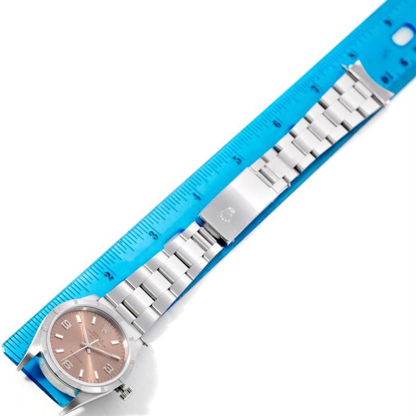 The Rolex Air-King 14010 Men's Stainless Steel Pink Dial 14010 Men's Stainless Steel Pink Dial watch is shown from a top-down angle, displaying its face, bracelet, and clasp alongside a ruler for scale.