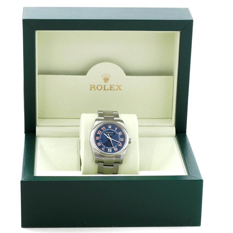 The Rolex Air-King 114200 Men's Stainless Steel Blue Dial 114200 Men's Stainless Steel Blue Dial watch is displayed frontally inside its open green and beige Rolex-branded box.