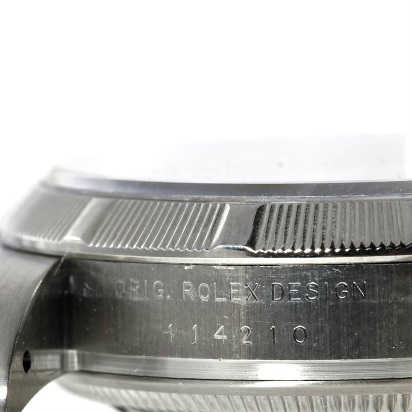 This image shows a close-up, side angle of the bezel and case of a Rolex Air-King 114200 Men's Stainless Steel Silver Dial 114200 Men's Stainless Steel Silver Dial watch, highlighting its engraving and design.