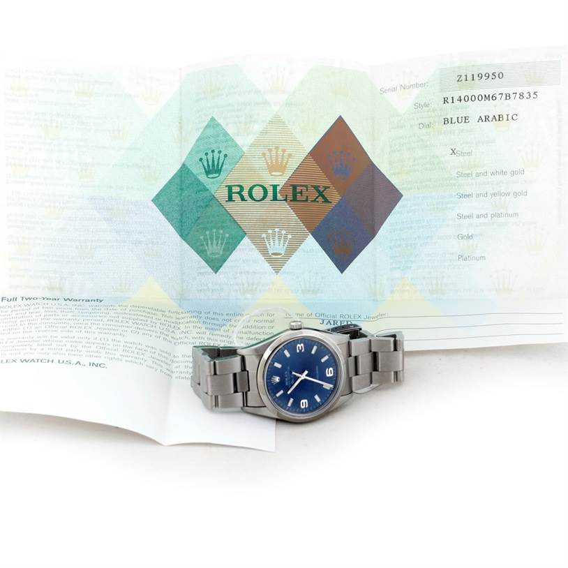 The Rolex Air-King 14000 Men's Stainless Steel Blue Dial 14000 Men's Stainless Steel Blue Dial watch is shown face-up with its warranty paperwork in the background.