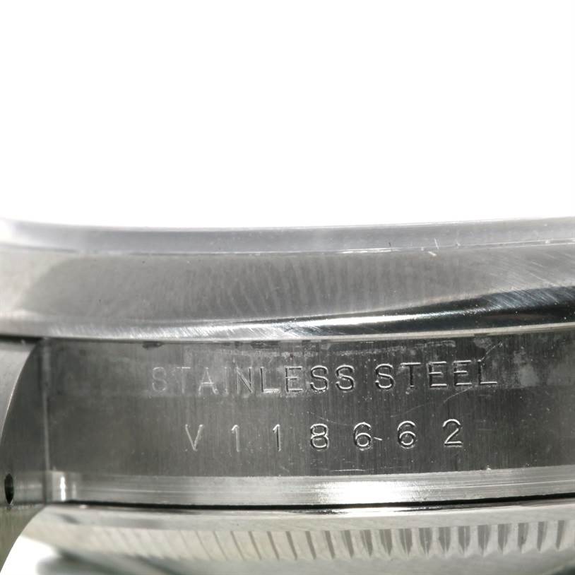 This image shows a close-up side view of the case back of a Rolex Air-King 114200 Men's Stainless Steel Blue Dial 114200 Men's Stainless Steel Blue Dial watch, highlighting the serial number and "Stainless Steel" engraving.