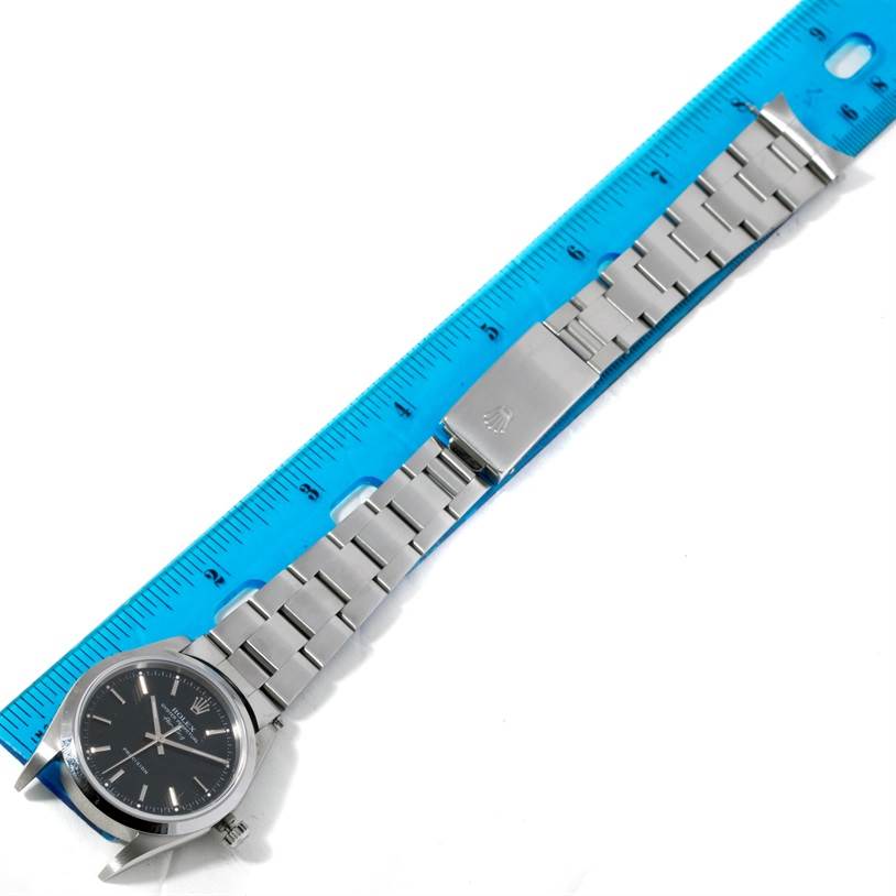 The Rolex Air-King 14000 Men's Stainless Steel Black Dial 14000 Men's Stainless Steel Black Dial watch is shown in a top-down angle, displaying its case, bracelet, and clasp, measured against a blue ruler.