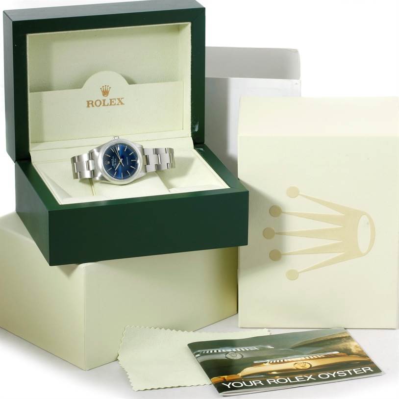 The Rolex Air-King 14000 Men's Stainless Steel Blue Dial 14000 Men's Stainless Steel Blue Dial watch is shown at a side angle in an open green box with additional packaging and accessories around it.