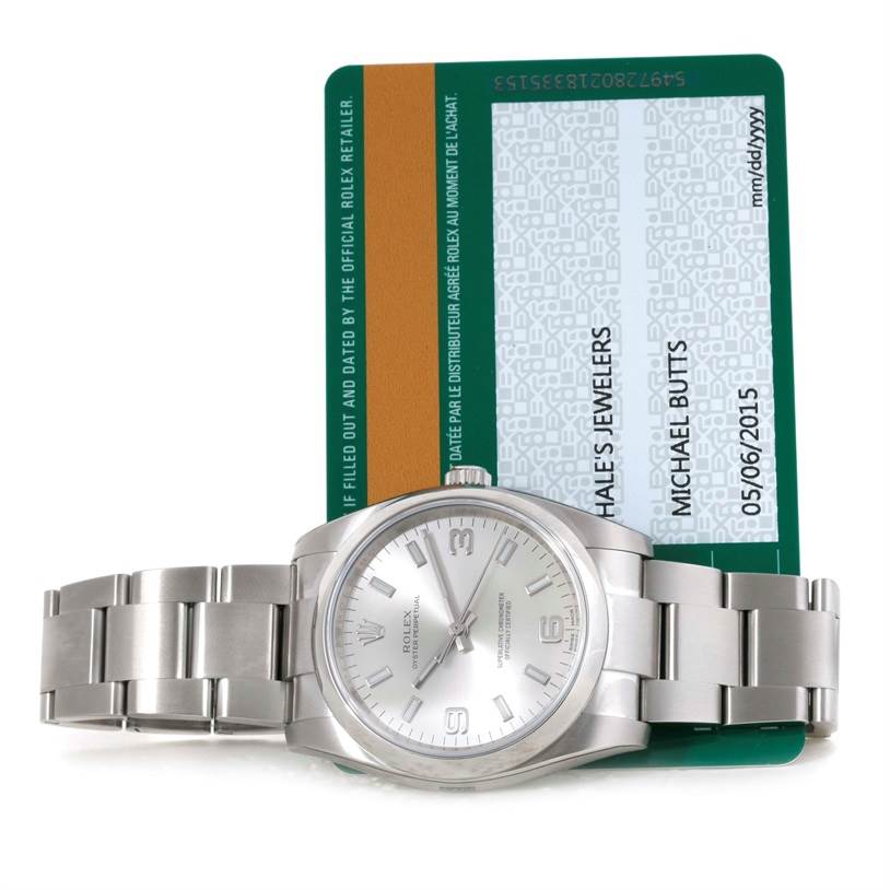 The image shows a Rolex Air-King 114200 Men's Stainless Steel Silver Dial 114200 Men's Stainless Steel Silver Dial watch lying flat with its warranty card partly visible behind it.