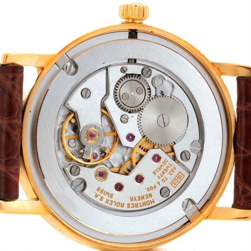 The image shows the back view of a Rolex Cellini 5115 Men
s Yellow Gold Champagne Dial 5115 Men
s Yellow Gold Champagne Dial watch, highlighting its intricate mechanical movement and gears.