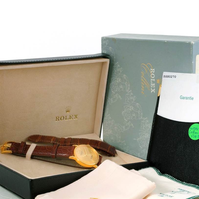 The image shows a Rolex Cellini 5115 Men
s Yellow Gold Champagne Dial 5115 Men
s Yellow Gold Champagne Dial watch from a front angle, alongside its box, warranty card, and a cleaning cloth.