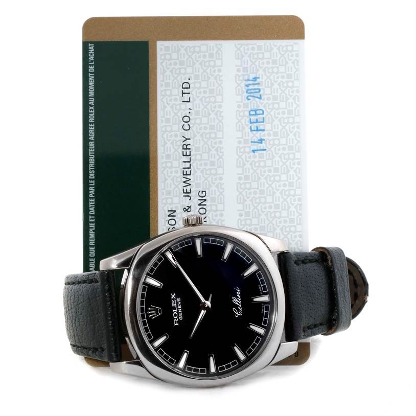 This image shows a front view of the Rolex Cellini 4243 Men's White Gold Black Dial 4243 Men's White Gold Black Dial watch with a black leather strap and a warranty card in the background.