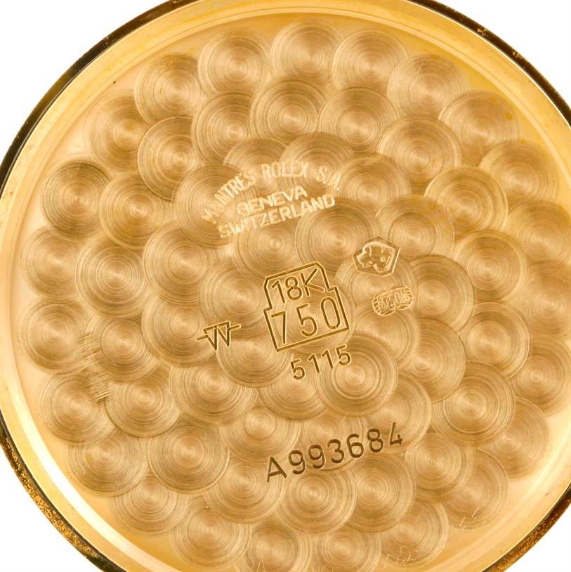 The image shows the 18K gold back casing of a Rolex Cellini 5115 Men
s Yellow Gold Silver Dial 5115 Men
s Yellow Gold Silver Dial watch, featuring engravings and hallmarks.