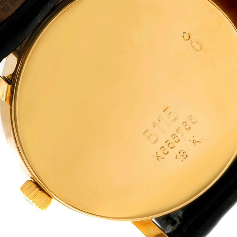 The image shows the back case of a Rolex Cellini 5115 Men
s Yellow Gold Mother of Pearl Dial 5115 Men
s Yellow Gold Mother of Pearl Dial model watch displaying its inscriptions and the crown.