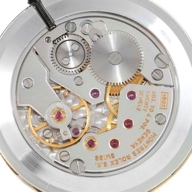The image shows a close-up view of the movement of a Rolex Cellini 5112 Men
s Yellow Gold Champagne Dial 5112 Men
s Yellow Gold Champagne Dial watch, highlighting the gears, jewels, and intricate mechanisms.