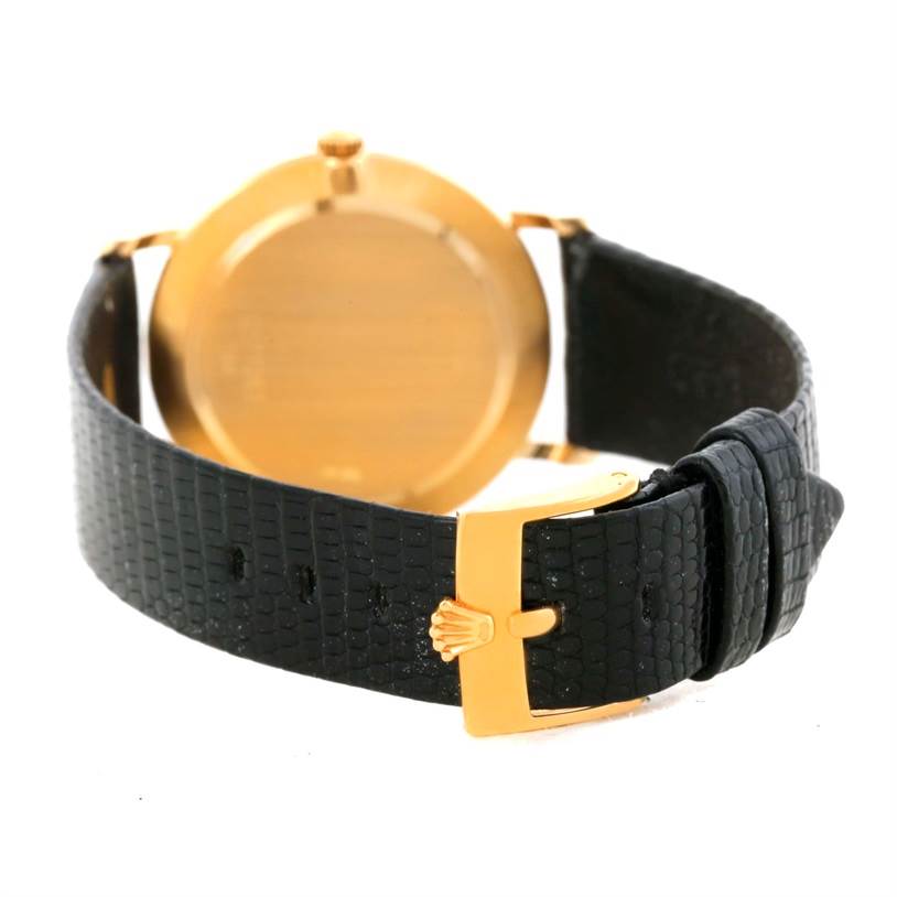 The image shows the back view of a Rolex Cellini 5112 Men's Yellow Gold Beige Dial 5112 Men's Yellow Gold Beige Dial watch, highlighting its golden case and black leather strap with a golden buckle.