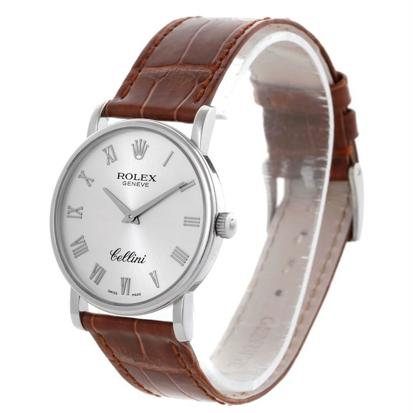 The Rolex Cellini 5115 Men's White Gold Silver Dial 5115 Men's White Gold Silver Dial watch is shown from a side angle, displaying the face, Roman numerals, crown, and brown leather strap.